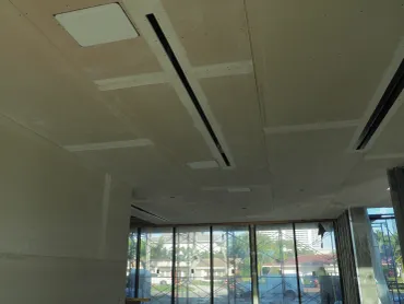 Coffered ceiling panels hung above a room with floor-to-ceiling windows