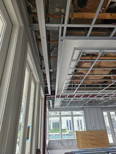 Ceiling framing and hung drywall in a room overlooking a pool