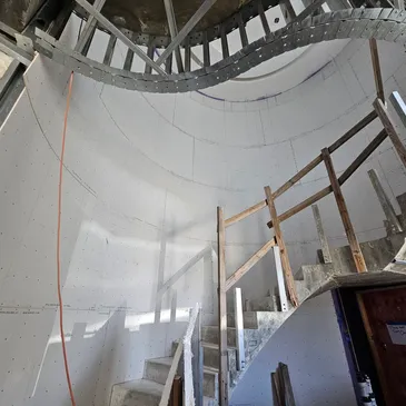 Drywall hung on the curved wall of a spiral stairwell