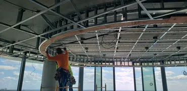 Worker installing a curved ceiling bulkhead in light-gauge metal framing